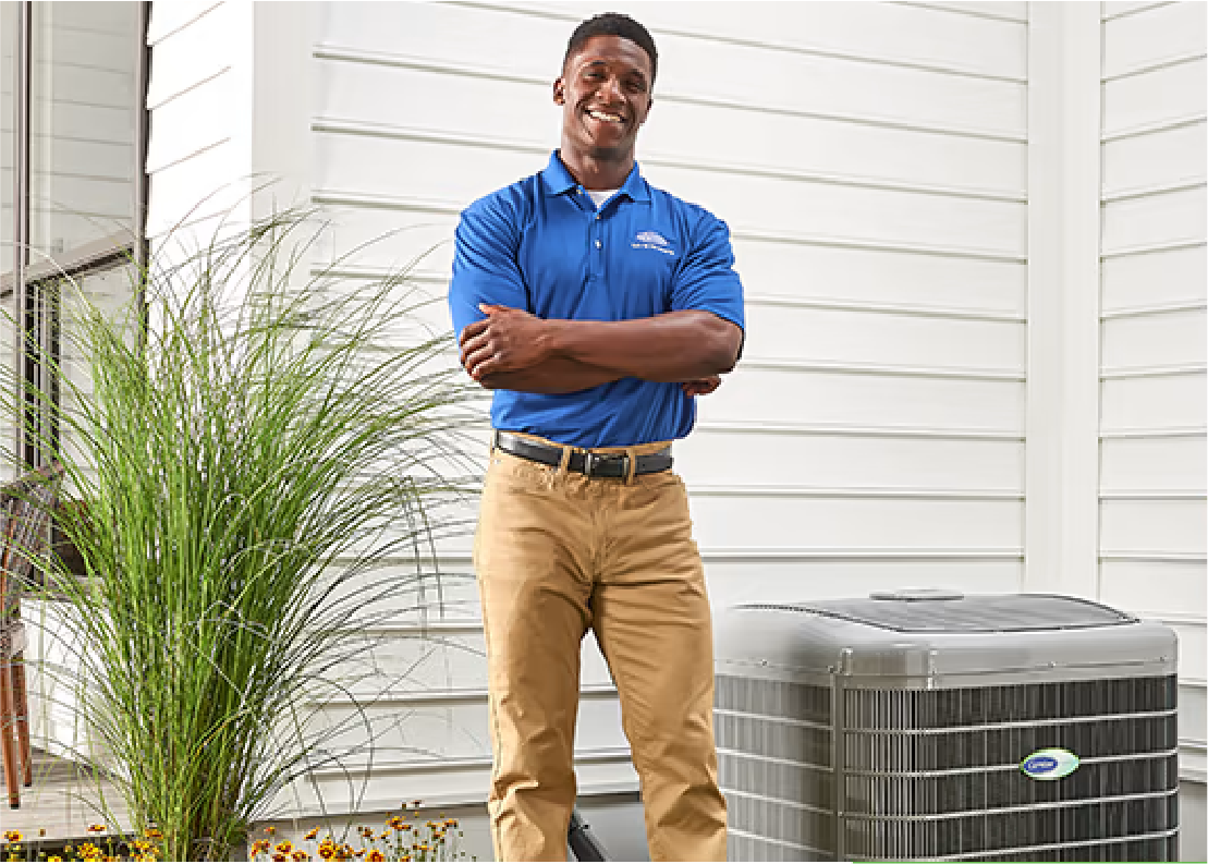 Man in front of carrier AC unit with hands cross and smiling | Advanced Heating and Air Conditioning