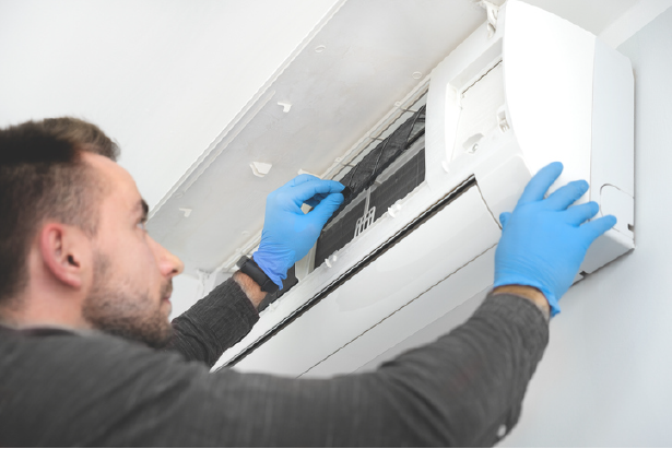 Technician checking ductless AC system | Advanced Heating and Air Conditioning