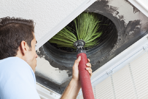 Man cleaning air ducts in home. | Advanced Heating and Air Conditioning