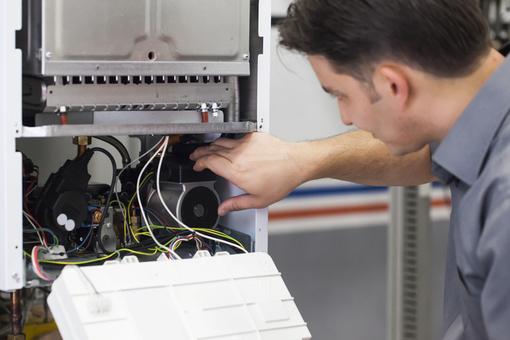 Technician servicing heating boiler | Advanced Heating and Air Conditioning