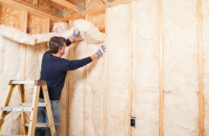 Construction Worker Insulating Wall with Fiberglass Batt | Advanced Heating and Air Conditioning