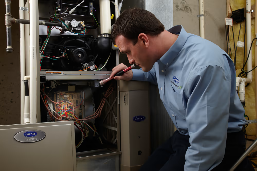 carrier technician looking at furnace | Advanced Heating and Air Conditioning